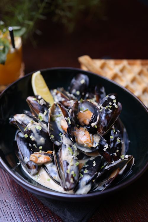 Free Delicious mussels in a creamy sauce served with waffles and a lemon wedge. Stock Photo
