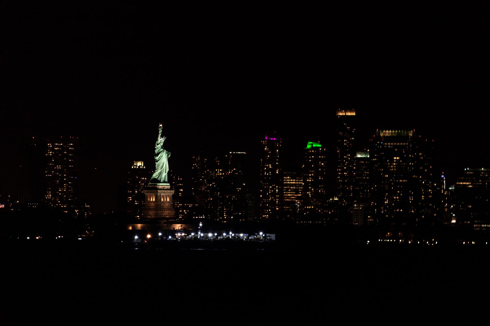 Stunning view of New York City's skyline featuring the illuminated Statue of Liberty during the night.