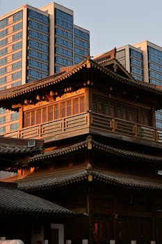 A traditional Chinese building contrasted with modern skyscrapers at sunset.