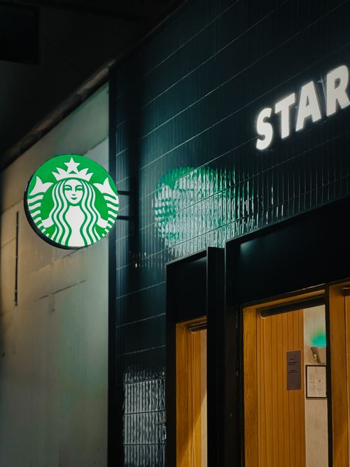 Free Illuminated Starbucks sign and entrance at night, showcasing cafe culture. Stock Photo