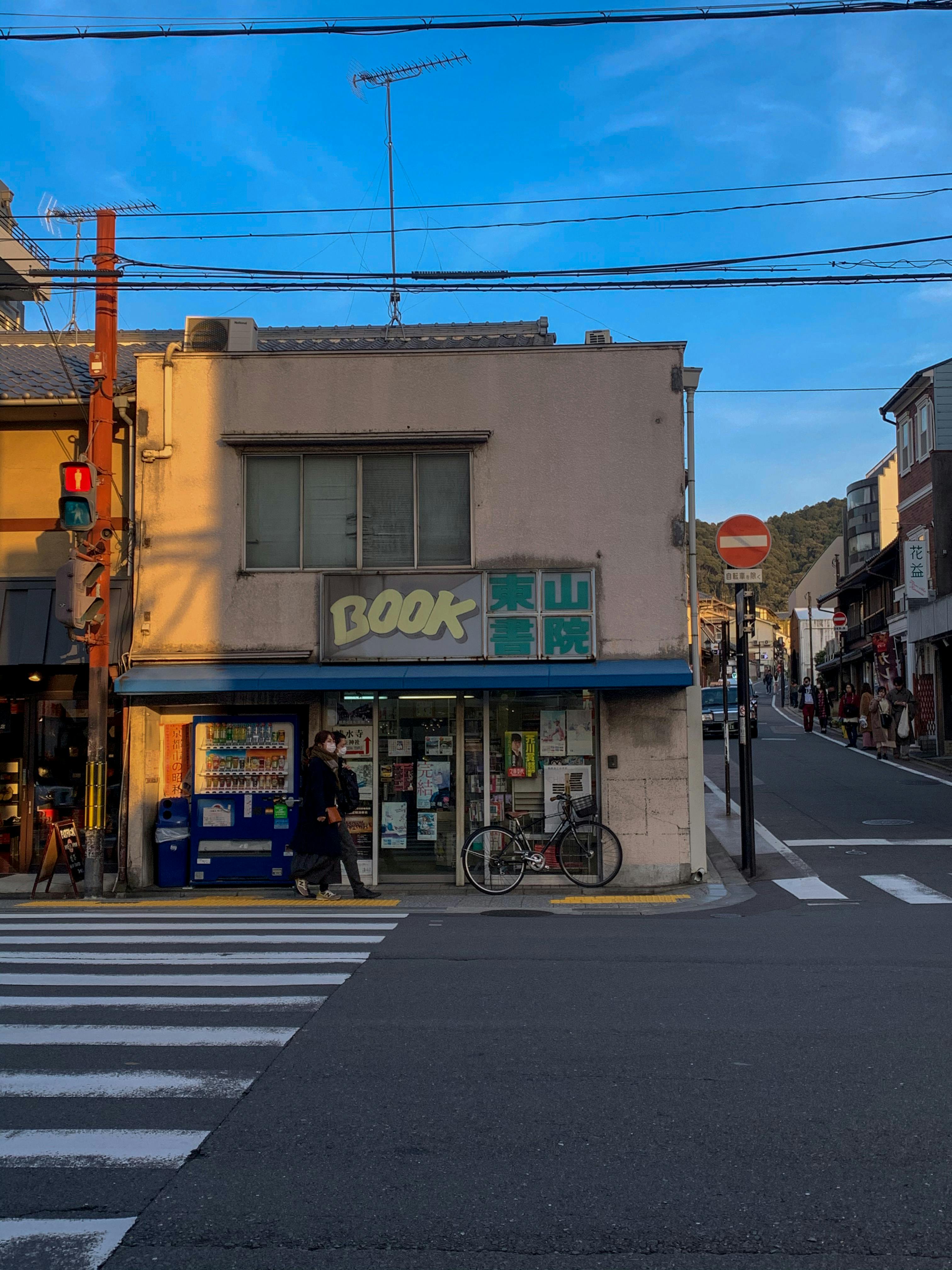 A traditional bookstore in Kyoto, Japan, captured during a serene dusk with ambient street activity.