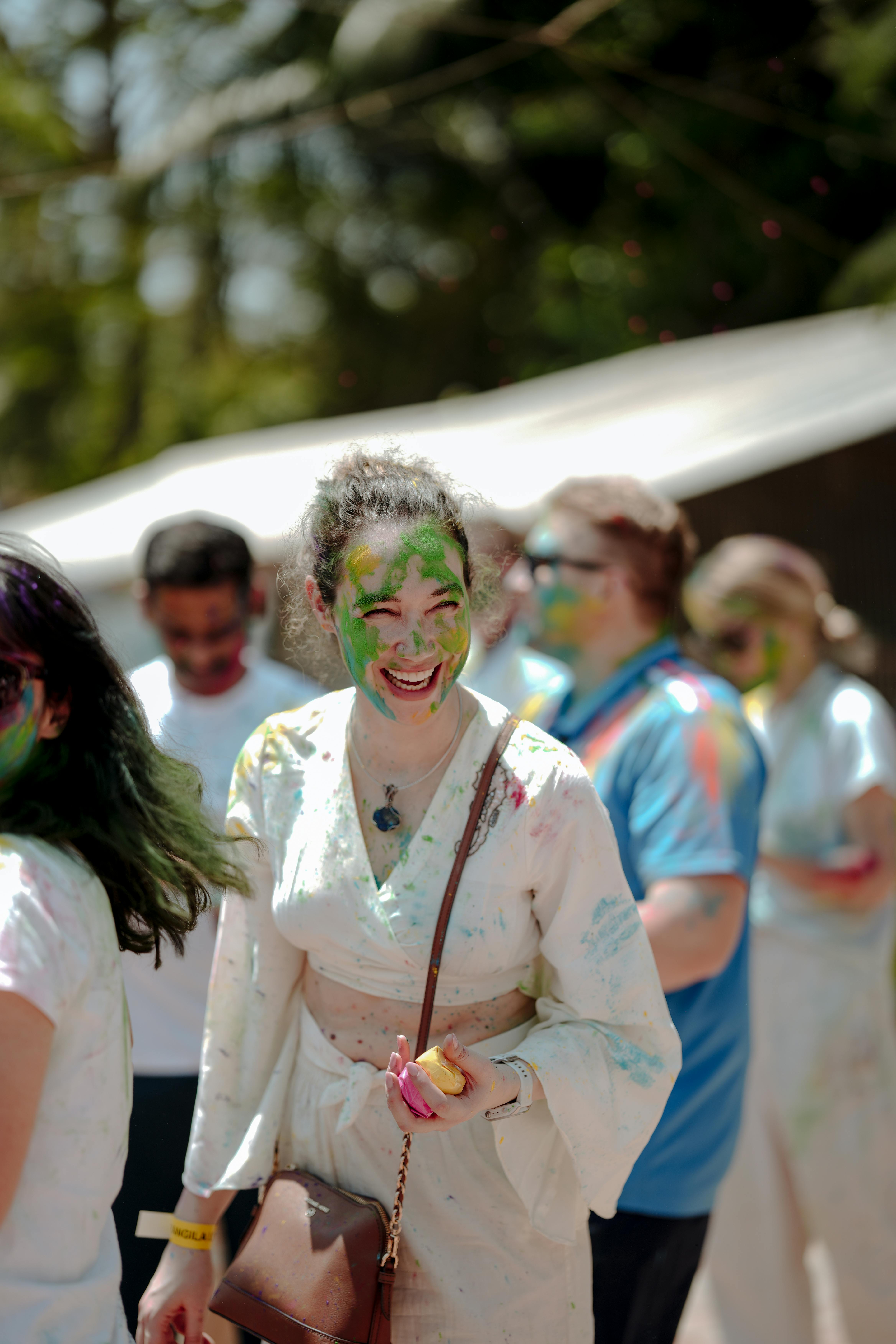 People enjoying Holi festival with vibrant colors and joyful expressions outdoors.