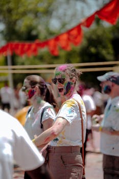 People enjoying a vibrant outdoor festival with colorful powders, fun and joy.