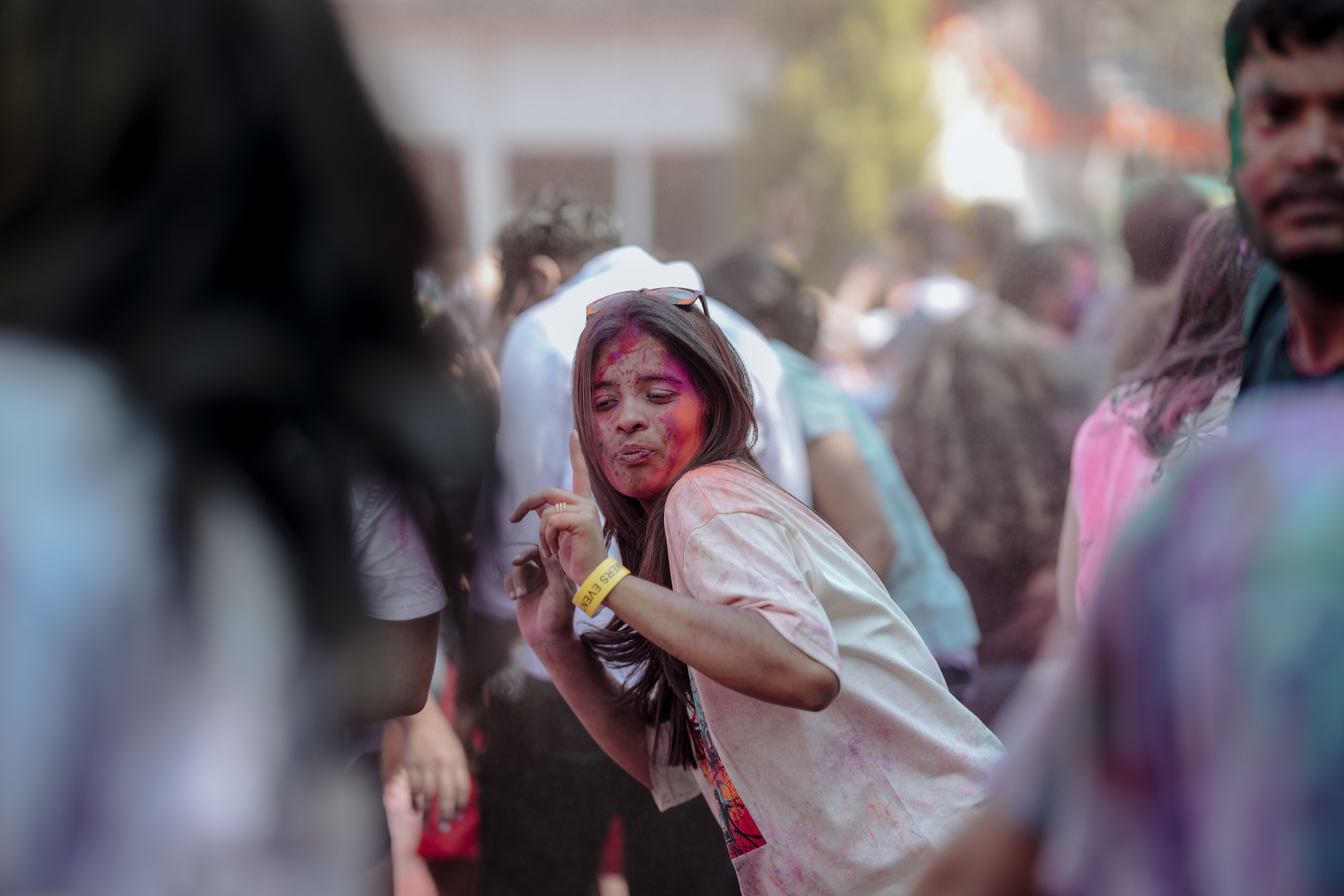 A young woman with pink powder on her face dances at a Holi color celebration, the festival Guyanese families call Phagwah