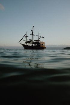 A serene pirate ship sailing on calm waters during sunset in Ubatuba, Brazil.