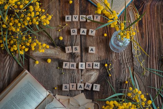 Flat lay of rustic wood, yellow flowers, and motivational quote.