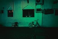 在迪拜黑暗而喜怒无常的街景中，一辆孤独的自行车靠在彩色墙上