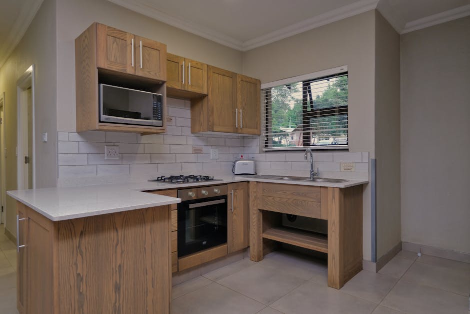 Sleek modern kitchen featuring wooden cabinetry and white countertops with natural lighting.