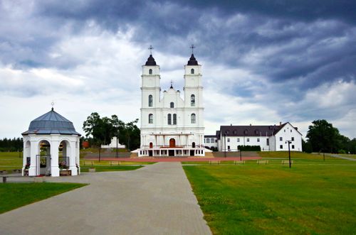 Free A beautiful white basilica in a serene outdoor setting with a dramatic cloudy sky in the background. Stock Photo