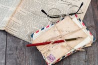 木制桌面上，旧信件、一支墨水笔和老式玻璃杯的特写镜头，旁边还放着一份报纸