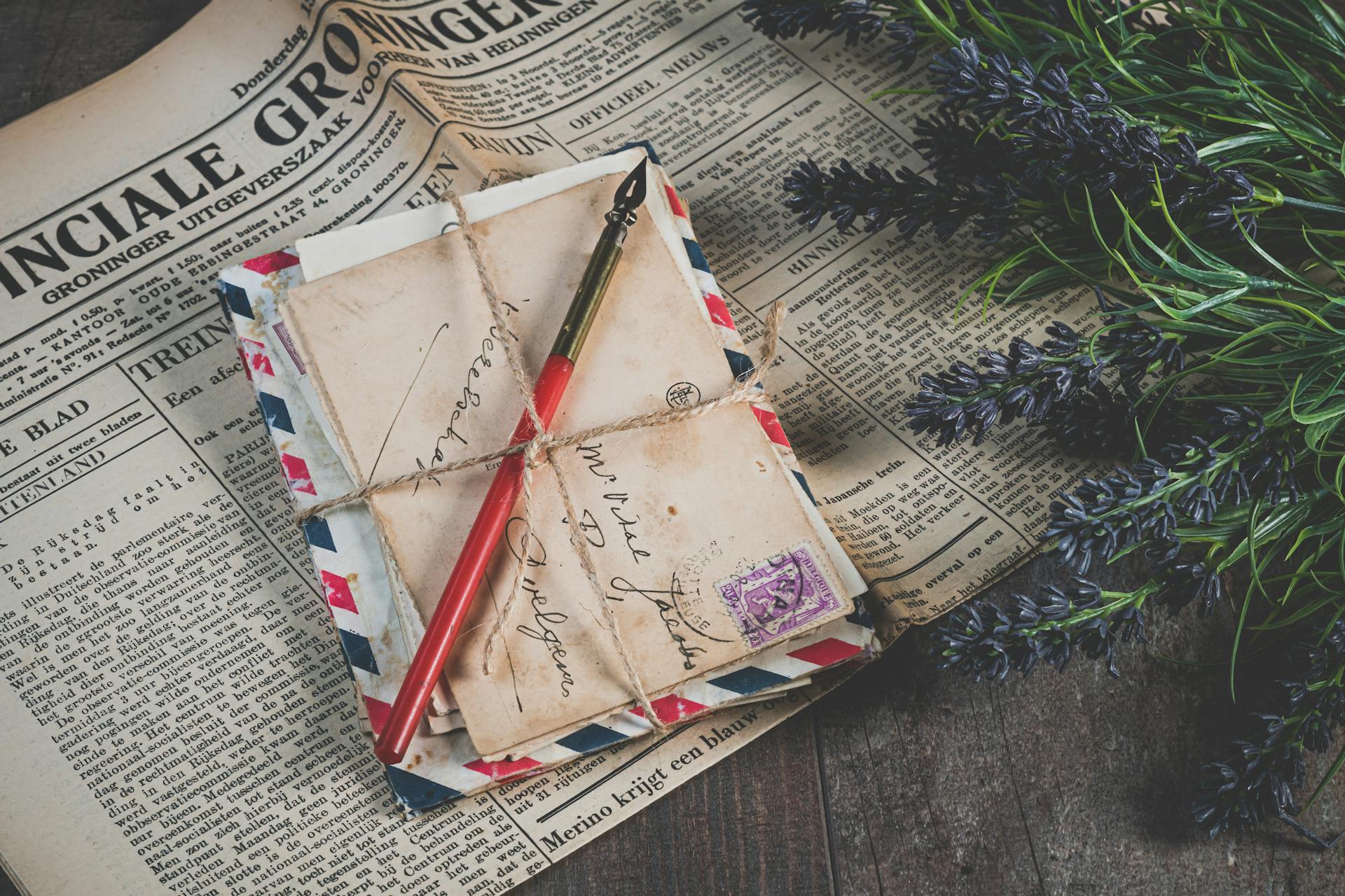 Old handwritten letters with vintage stamps and lavender on a newspaper background.