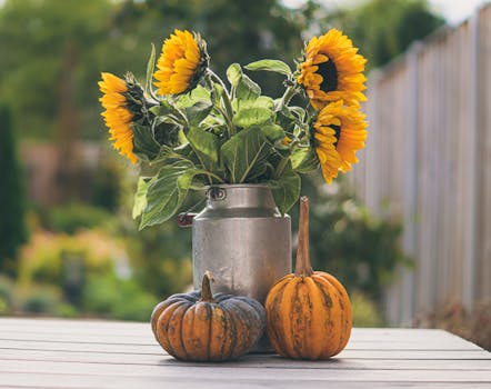 质朴的秋季布景中，向日葵插在金属罐里，南瓜摆在木桌上