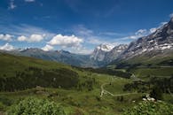 在晴朗的蓝天下，瑞士阿尔卑斯山郁郁葱葱的绿色山谷和雄伟的山脉展现出令人惊叹的景色