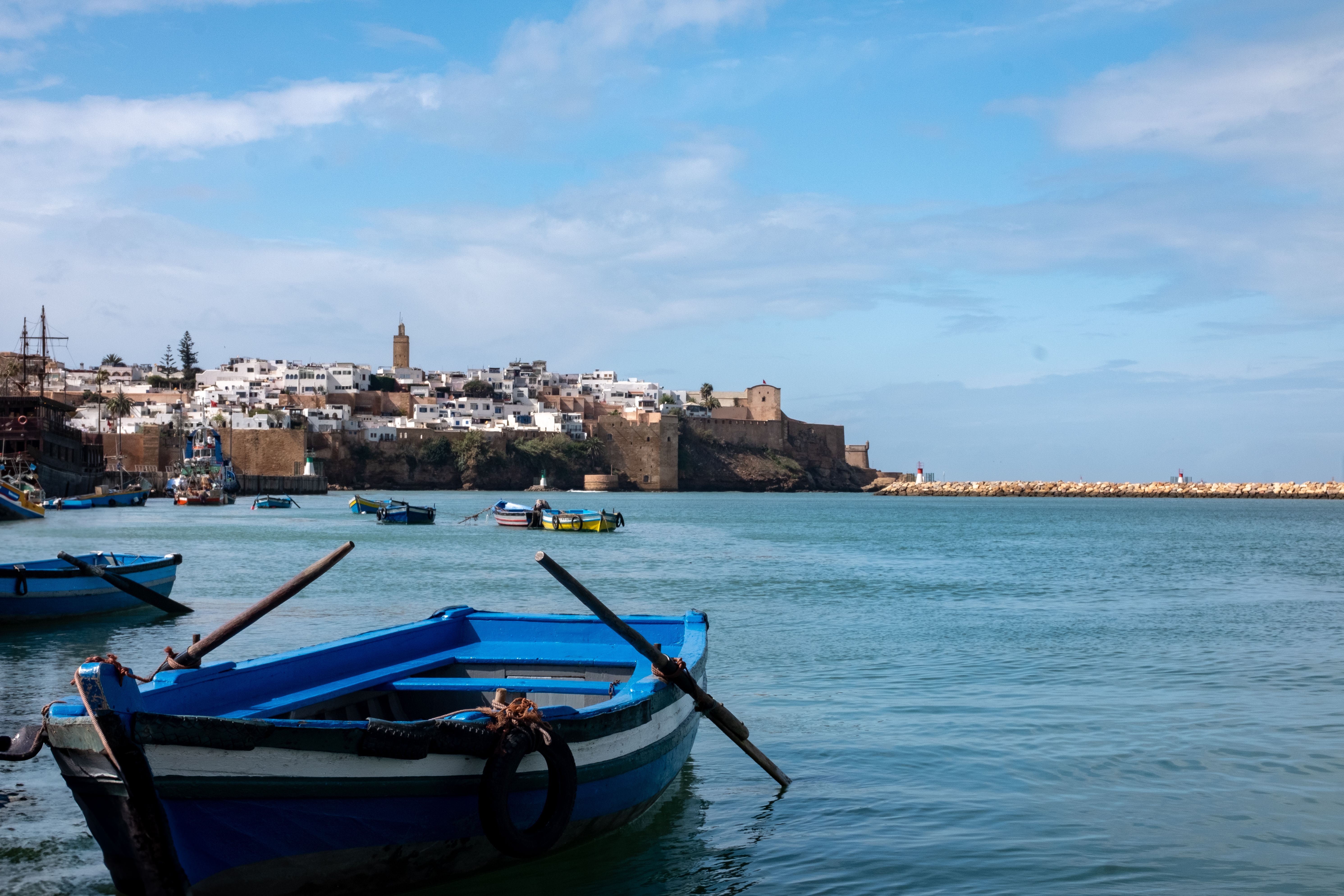 Vibrant blue boats on Bou Regreg River with Rabat's old city in the background.