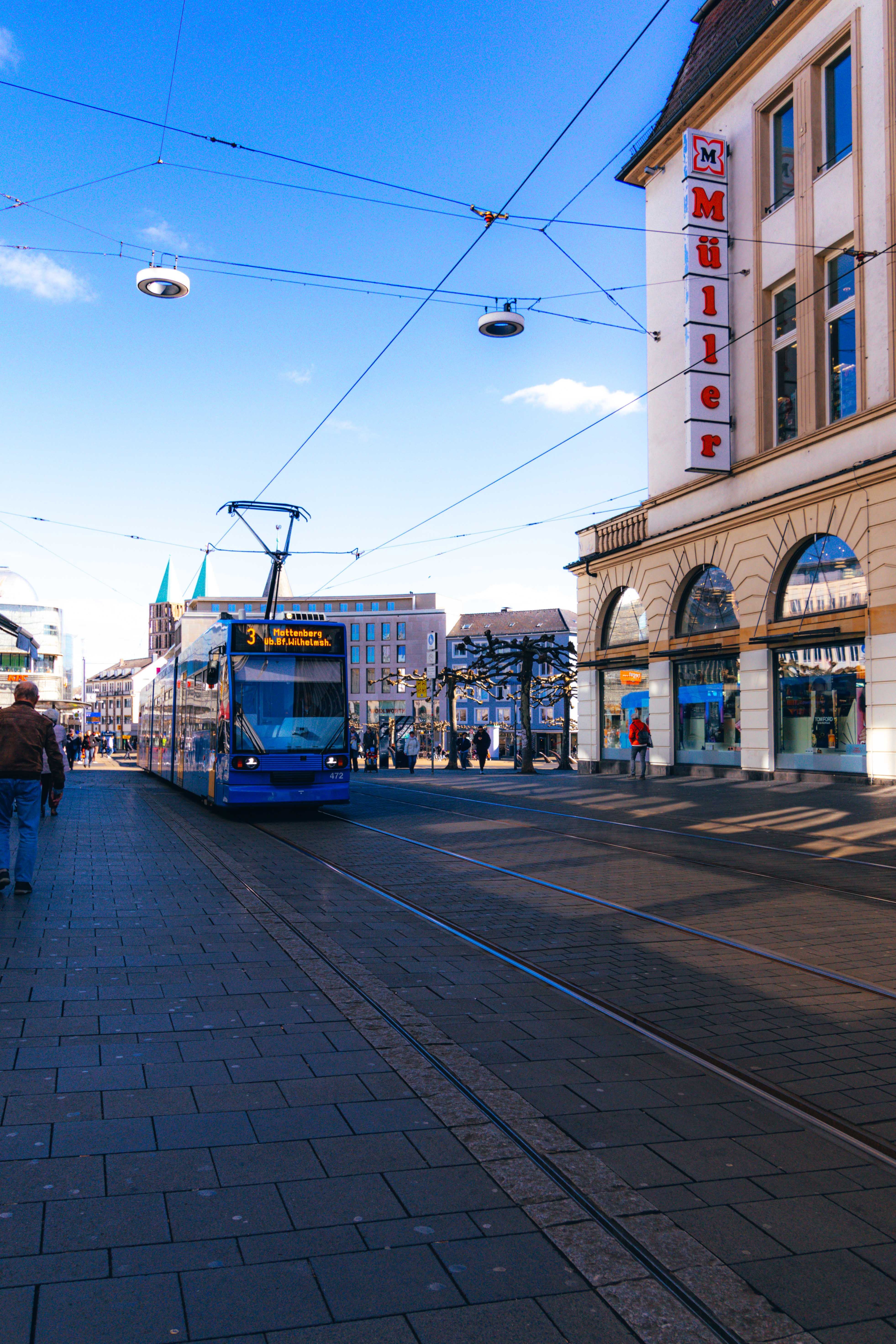 Blue tram on historic street in Würzburg, Bavaria, showcasing urban transport and architecture.