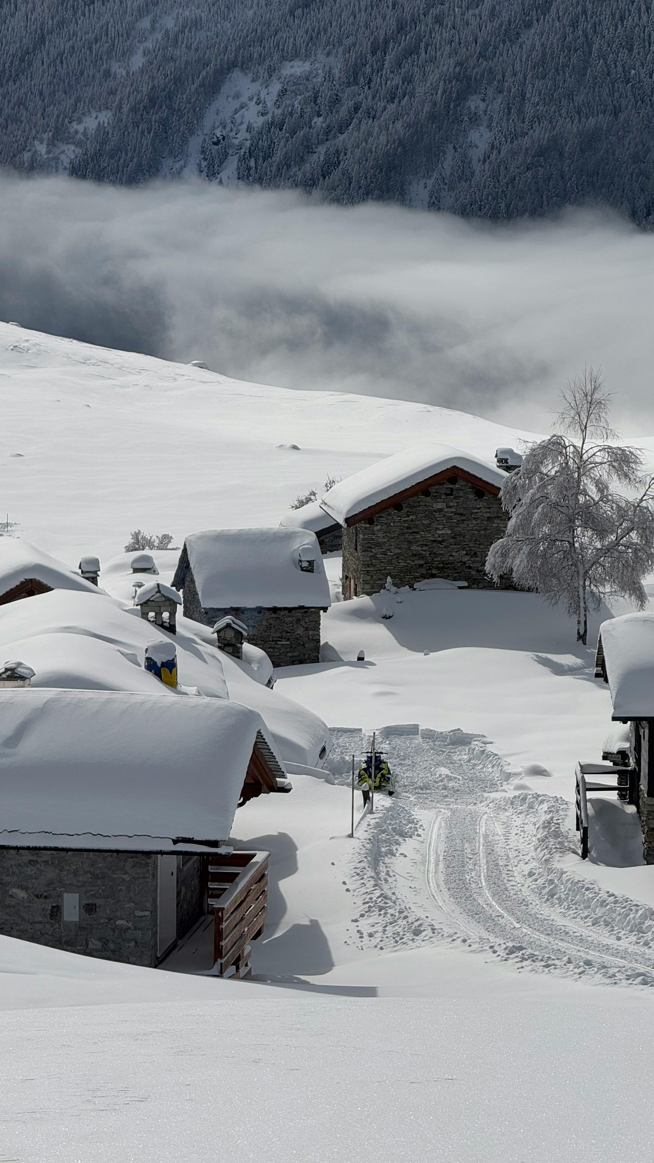 Gratis Pittoresco villaggio innevato con maestose montagne sullo sfondo, ideale per viaggi a tema invernale. Foto a disposizione