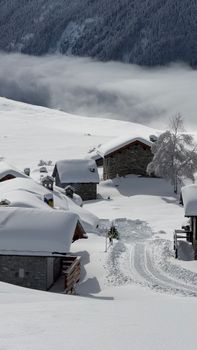 Picturesque snow-covered village against majestic mountain backdrop, ideal for winter travel themes.