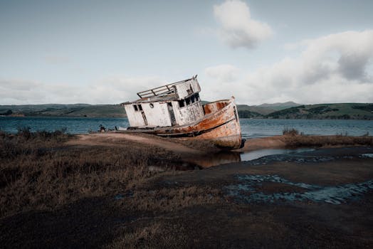 黎明时分，水面平静，云淡，一艘沉船停在岸边