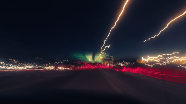 Long exposure shot capturing vibrant abstract light trails on a road at night.