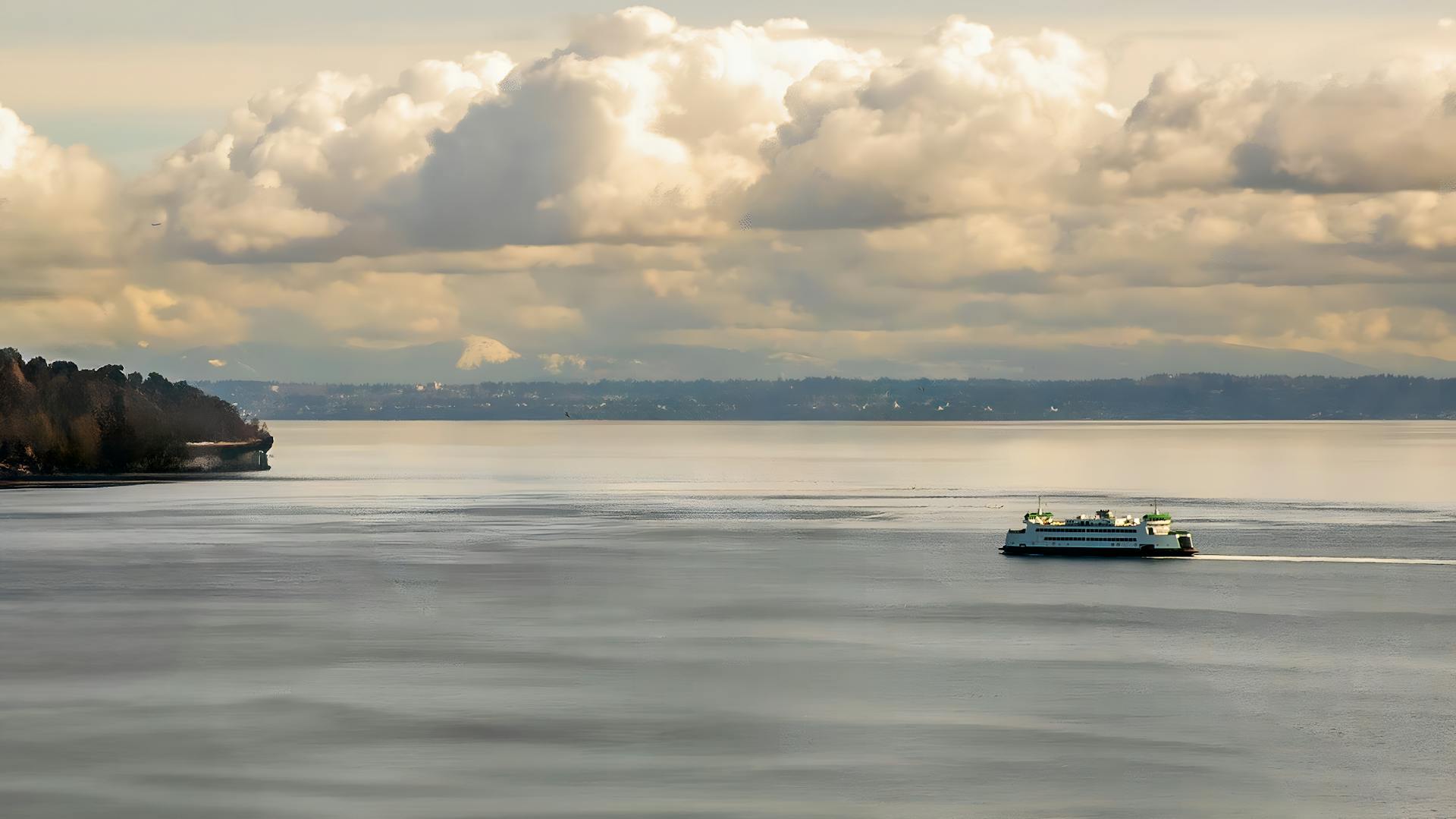 A ferry travels across Puget Sound in Tacoma, WA, under dramatic clouds.