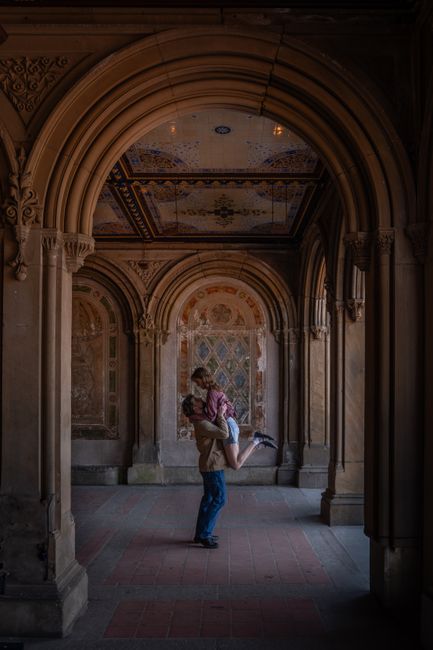A couple shares a romantic moment under the iconic arches of Central Park, NYC.
