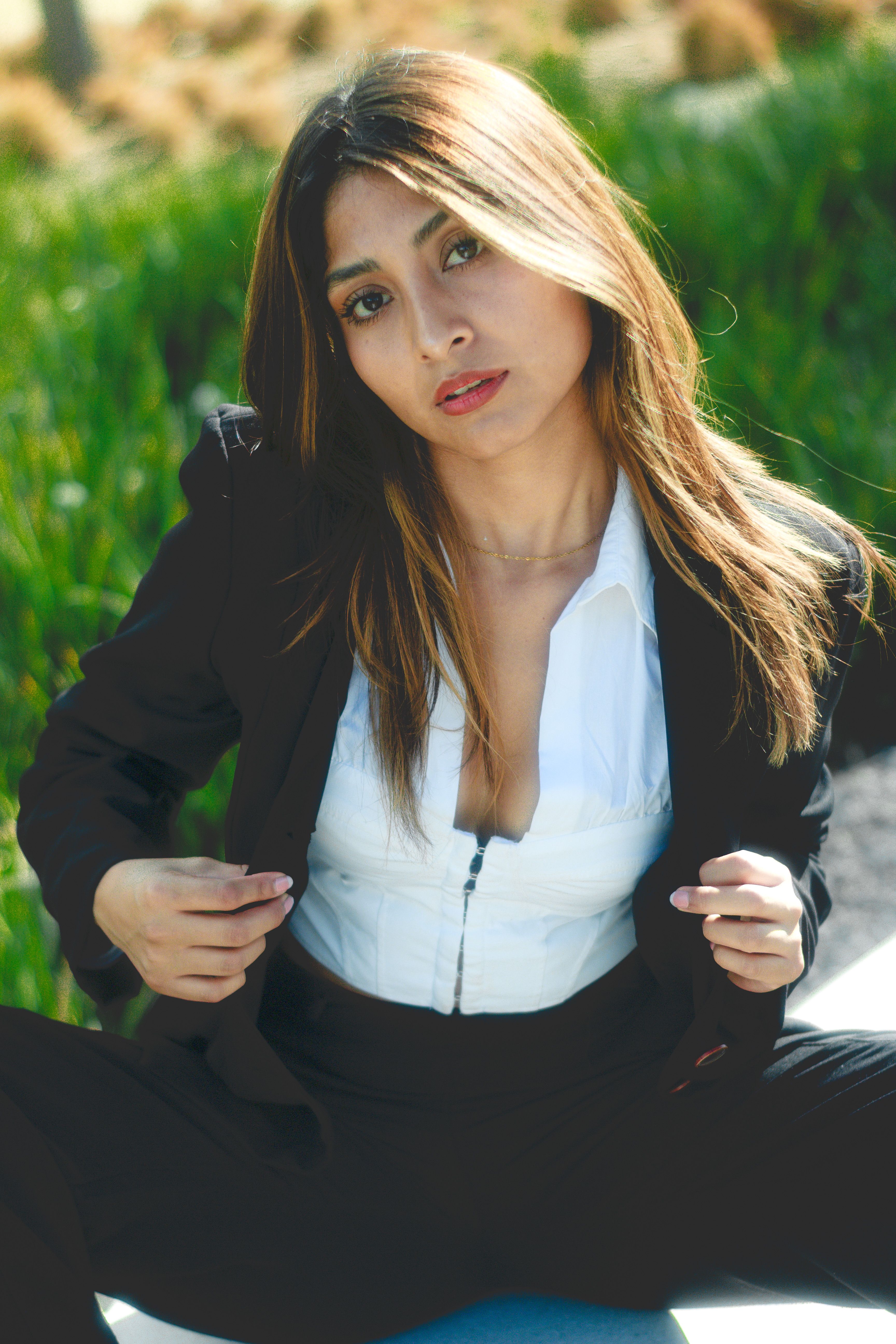 Portrait of a confident woman in business attire seated outdoors on a sunny day.