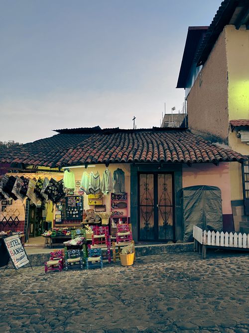 Free Rustic storefront in Tlalpujahua, showcasing colorful textiles and traditional crafts under a twilight sky. Stock Photo