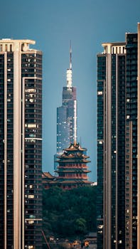A striking urban scene capturing a modern skyscraper and traditional pagoda between high-rise buildings.