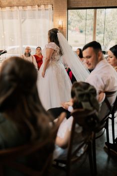 Bride in white dress speaks to seated guests at elegant indoor wedding venue. - Fotografer Sidoarjo
