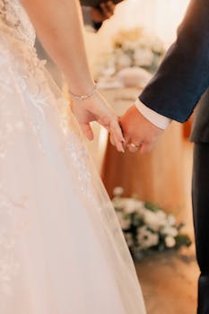 A couple holds hands during their wedding ceremony, symbolizing love and union.