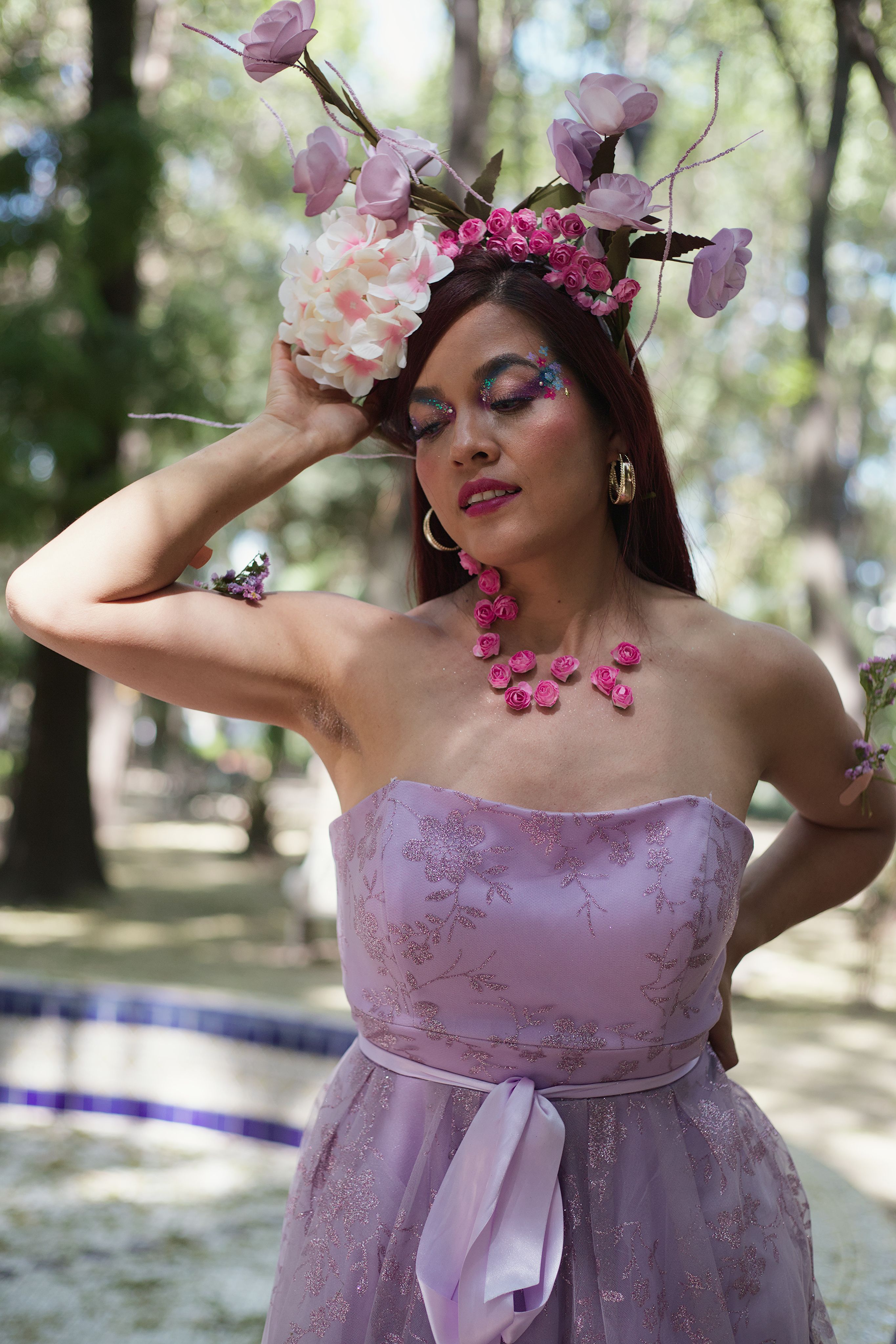 Fotomural Elegante mujer con vestido rosa y corona floral disfrutando de la naturaleza.