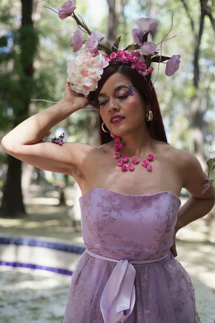 Fotomural Elegante mujer con vestido rosa y corona floral disfrutando de la naturaleza.