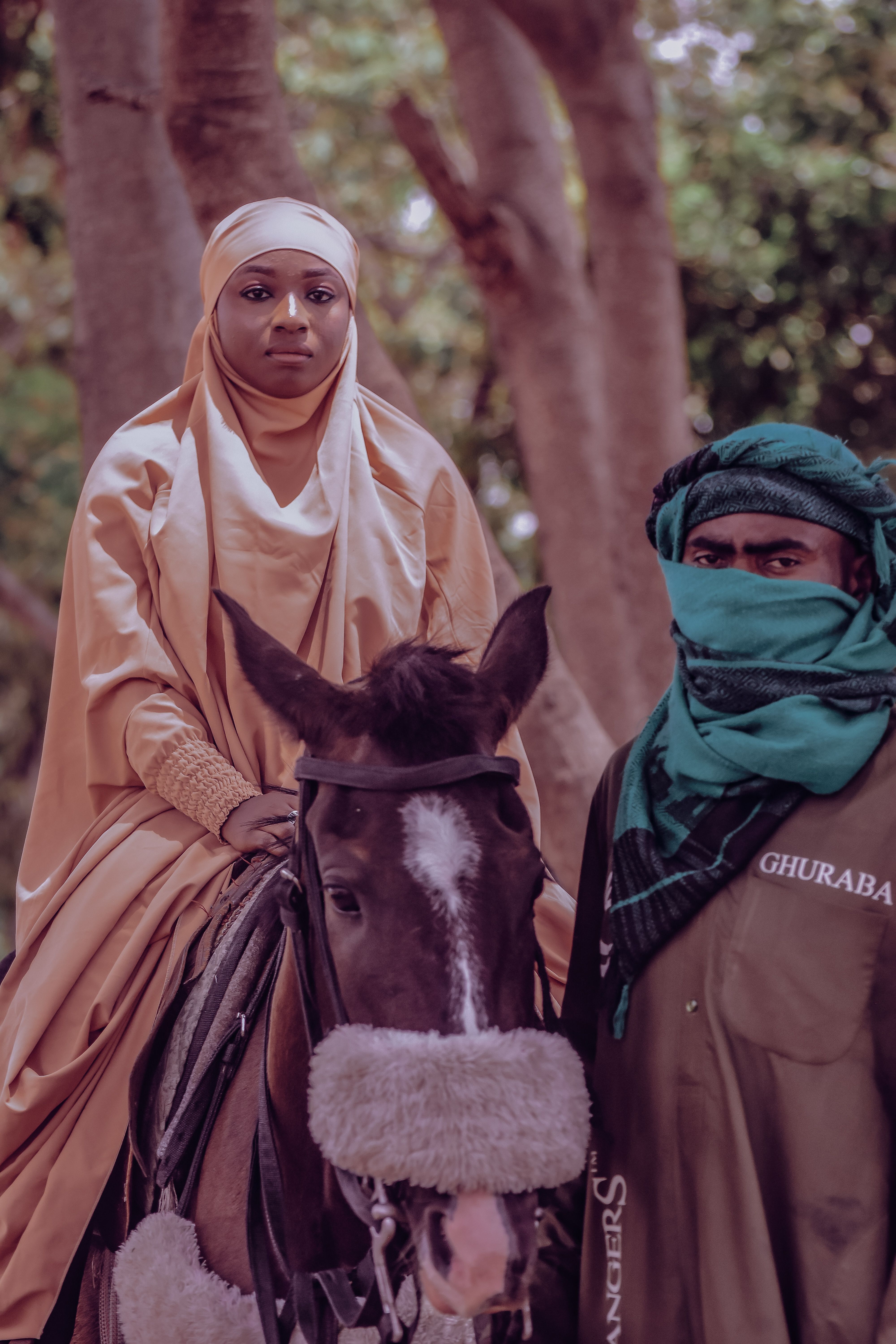 Elegant portrait of two adults in traditional clothing with a horse, outdoors.