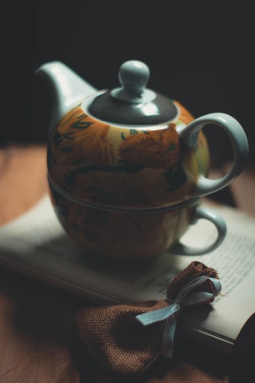Free Close-up of a handmade ceramic teapot placed on an open book with a tea bag. Stock Photo