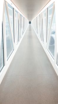 Long glass-panelled walkway at Dubai airport, showcasing modern architecture and symmetry.