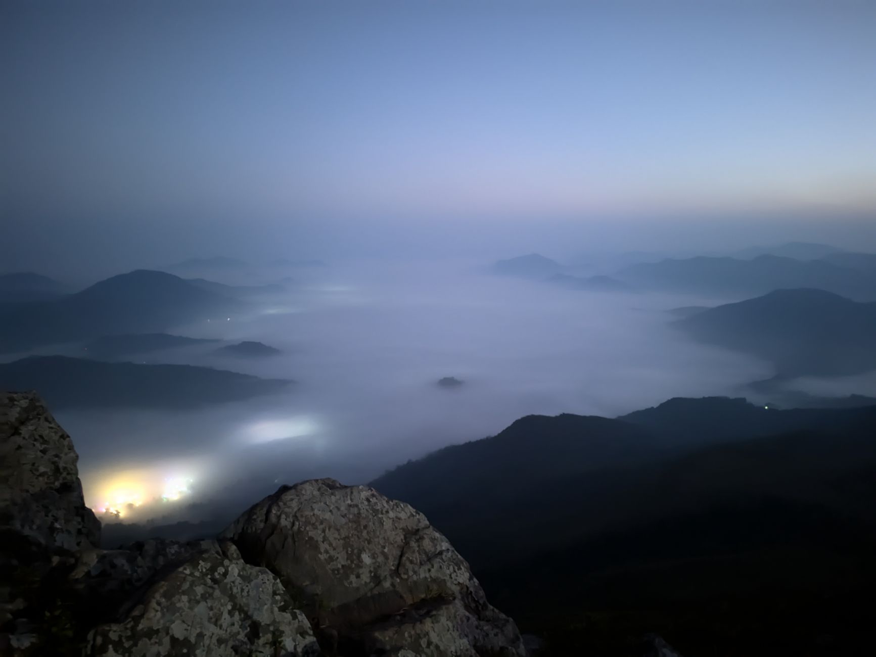 Serene mountain view shrouded in mist during twilight, offering a tranquil and mystical ambiance.