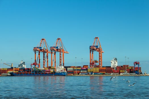 Colorful container port with large cranes and ships against a clear blue sky.