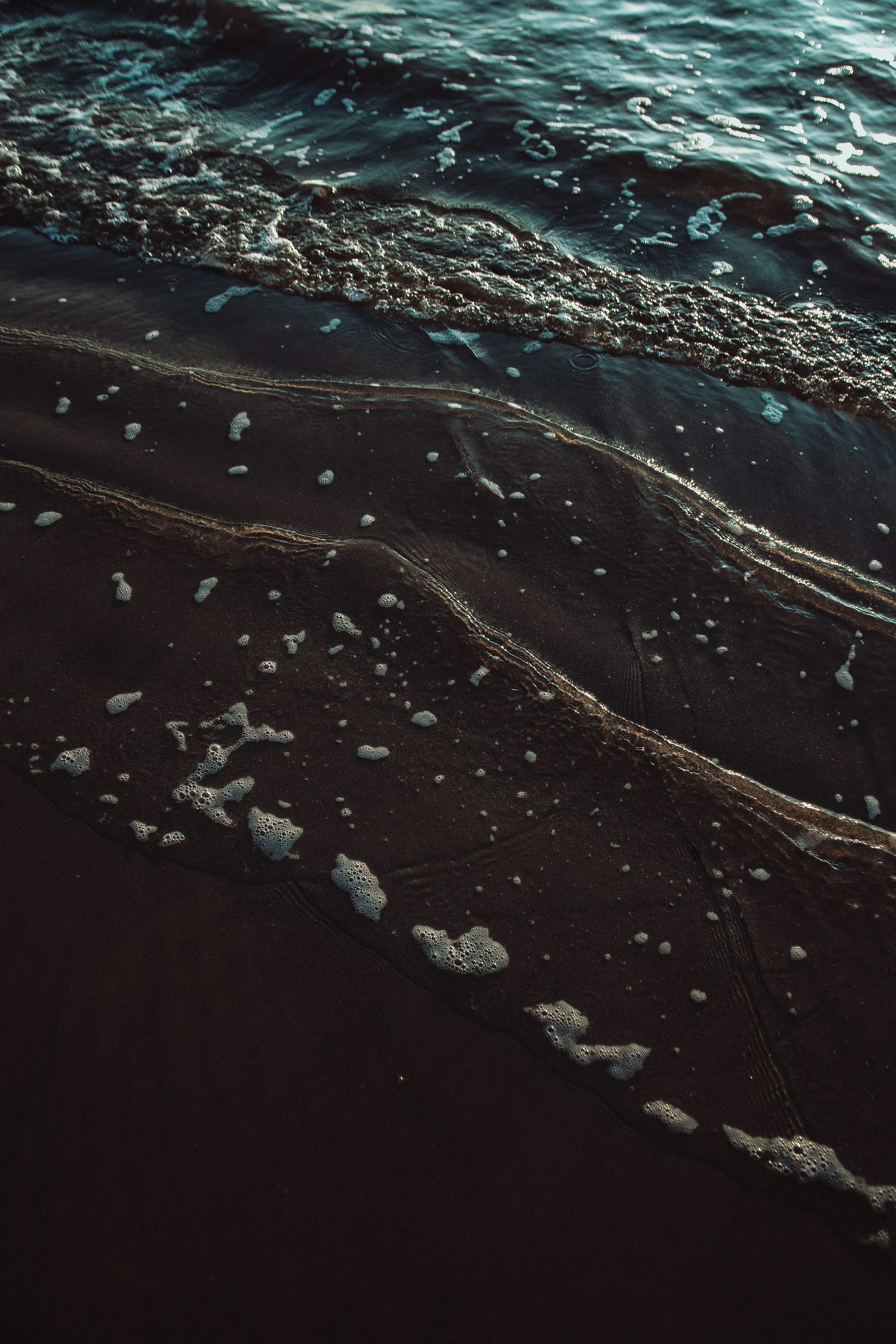 从高角度俯瞰宁静海滩上的轻柔波浪和海沫