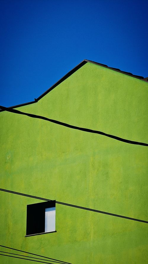 Free Bright green building facade with minimalistic design against clear blue sky. Stock Photo