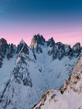 Stunning winter view of the snow-covered Dolomites under a pastel sky during sunset.