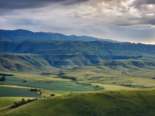 Free Breathtaking landscape of the Drakensberg mountains with lush greenery and dramatic cloudy sky. Stock Photo