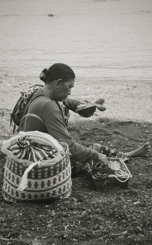 Free Local artisan crafting handmade goods on a Bali beach, showcasing traditional skills. Stock Photo