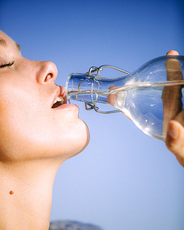 Woman Drinking Water From Glass Bottle: ways to cure dry skin on the face in two weeks