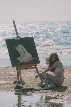 Woman in bikini painting on a beach easel by the ocean. Serene, summer vibes.