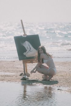 Artist painting on a serene beach with sunlight glistening on the ocean waves.