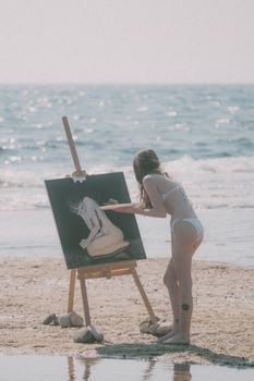A woman painting by the sea, capturing creative beach vibes on a sunny day.