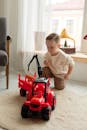 Child Playing with Red Toy Tractor Indoors
