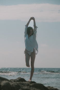 A woman enjoying a peaceful moment on a rocky beach, embracing the summer vibe.