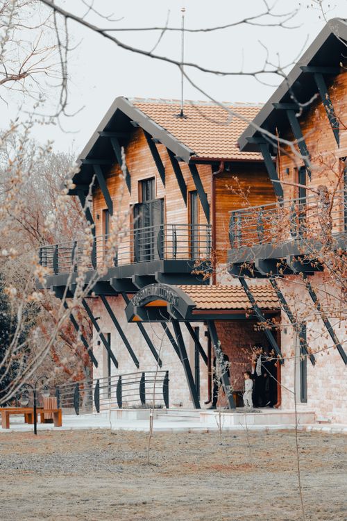 Free Stunning modern wooden house exterior featuring large windows and a tiled roof, showcasing elegant design. Stock Photo