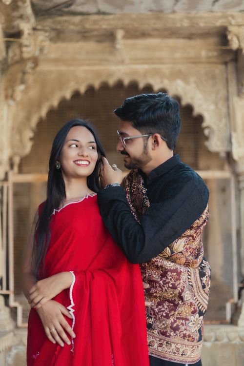Free Couple smiling and embracing in traditional attire at a historic site. Stock Photo